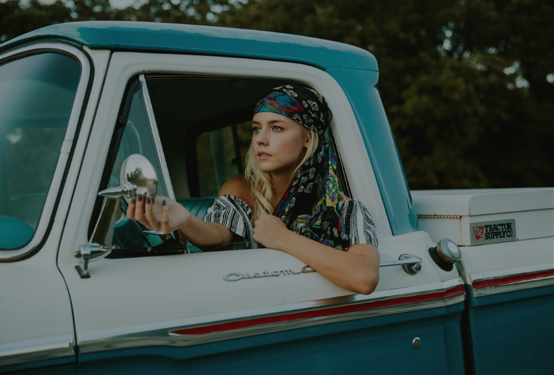 Stylish Travel blogger in a pickup truck heading on a road trip 
